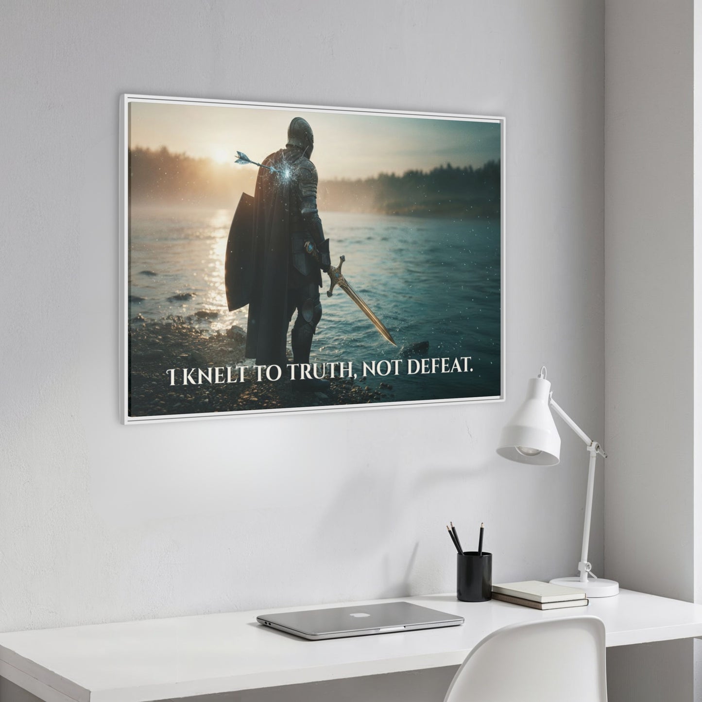 Angled white framed Chapter 1 canvas of a knight at the river with the quote ‘I knelt to truth, not defeat’ hanging above a clean white workspace.