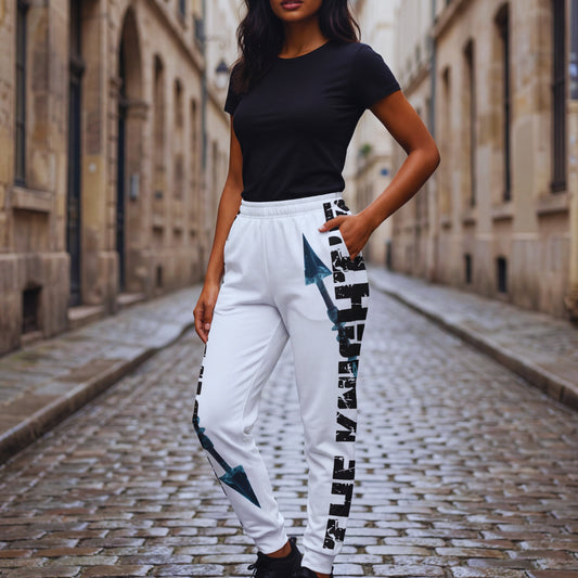 Three-quarter view of Amara wearing The Knight’s Path “Arrow One” white joggers, hands in pockets, showcasing the vertical text and blue crystal arrow along the leg.