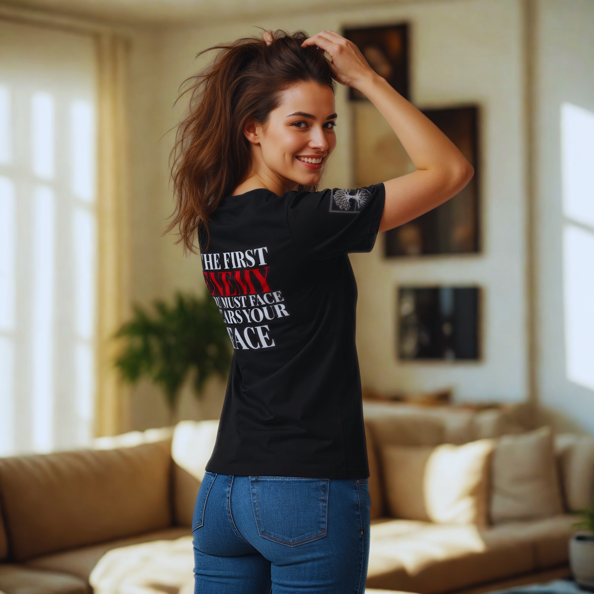 Back view, black organic t-shirt with “The first enemy you must face wears your face” quote (ENEMY in red); warm home interior, natural daylight.