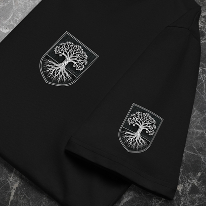 Flat-lay of black organic tee on stone surface; left-chest crest and sleeve crest; sharp DTFlex print detail.
