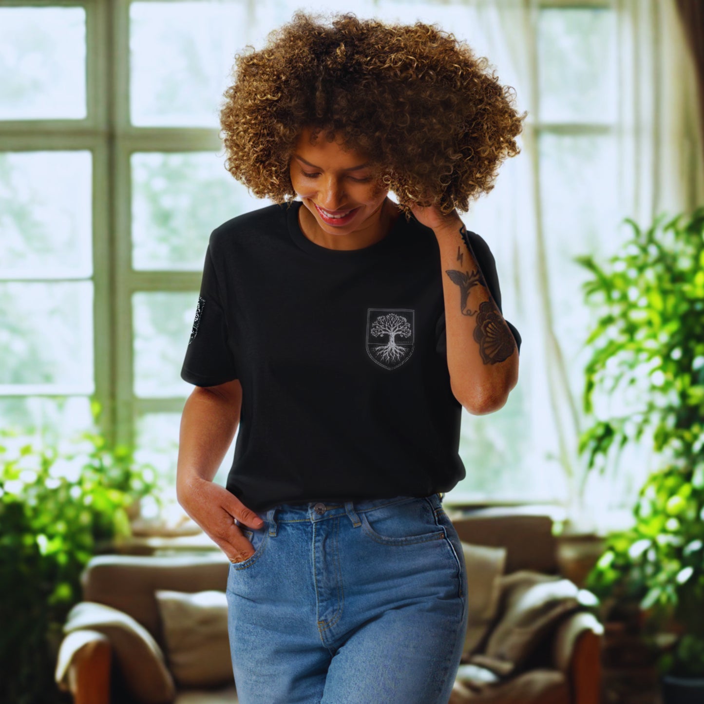 Lifestyle wide shot; black organic tee with chest crest; relaxed home setting, natural light.