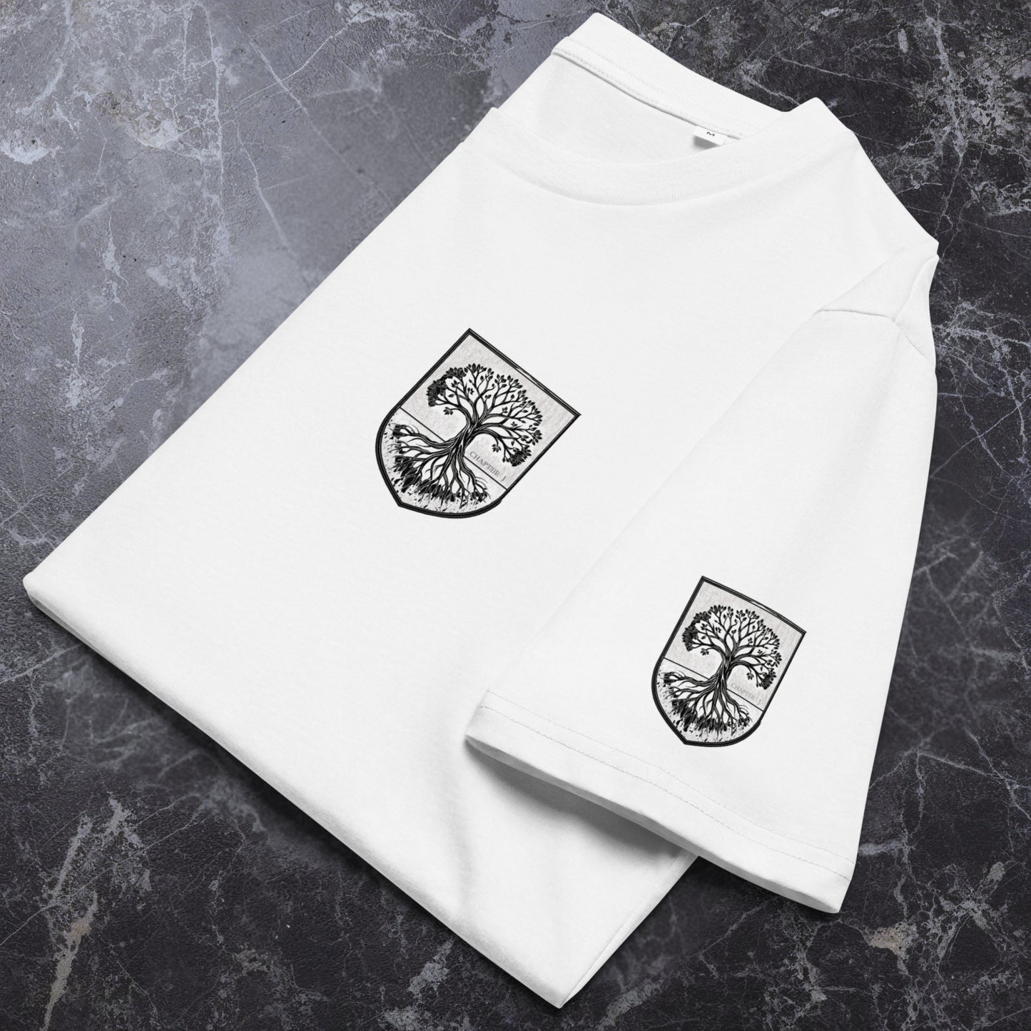 Flat-lay of white organic tee on stone surface; chest crest and sleeve crest visible; sharp black ink, DTFlex look.