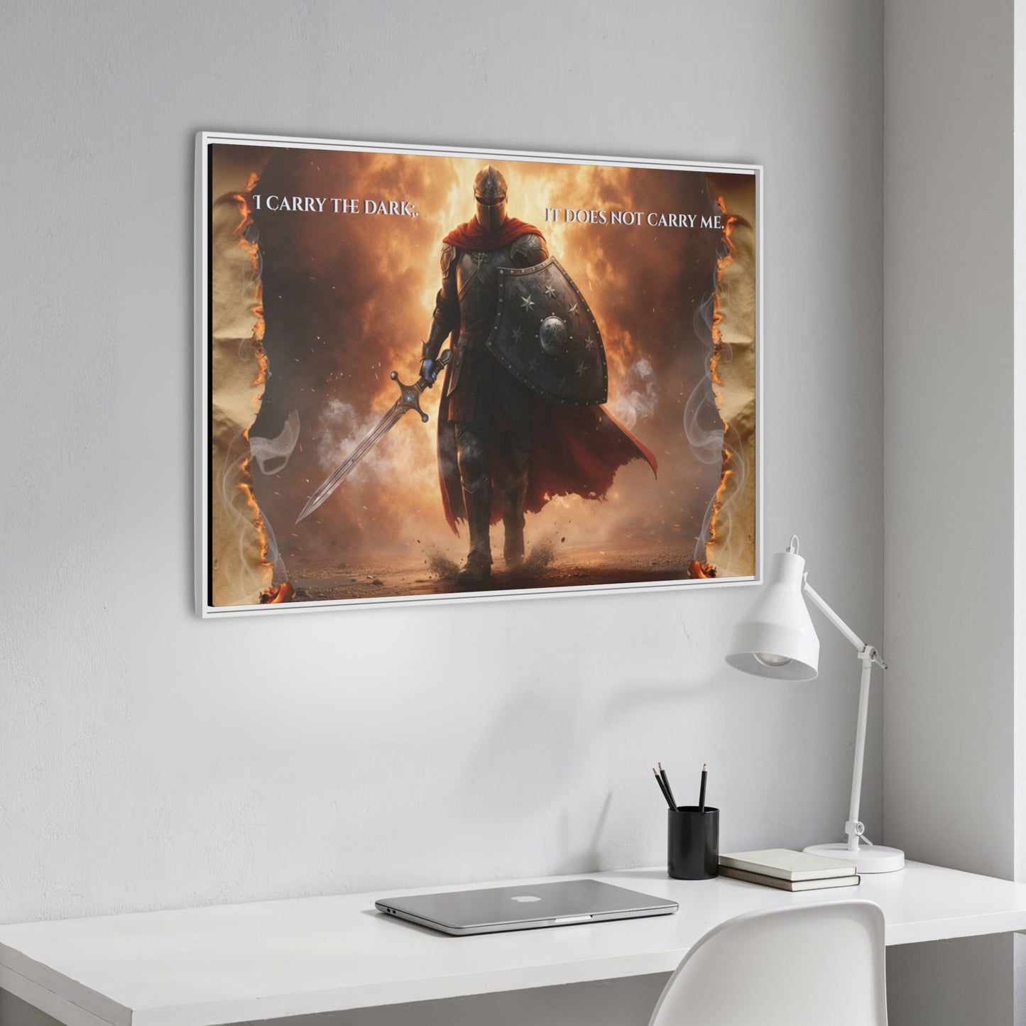 Angled close-up of the knight-in-fire framed canvas with the quote ‘I carry the dark; it does not carry me’ hanging above a minimalist white desk.