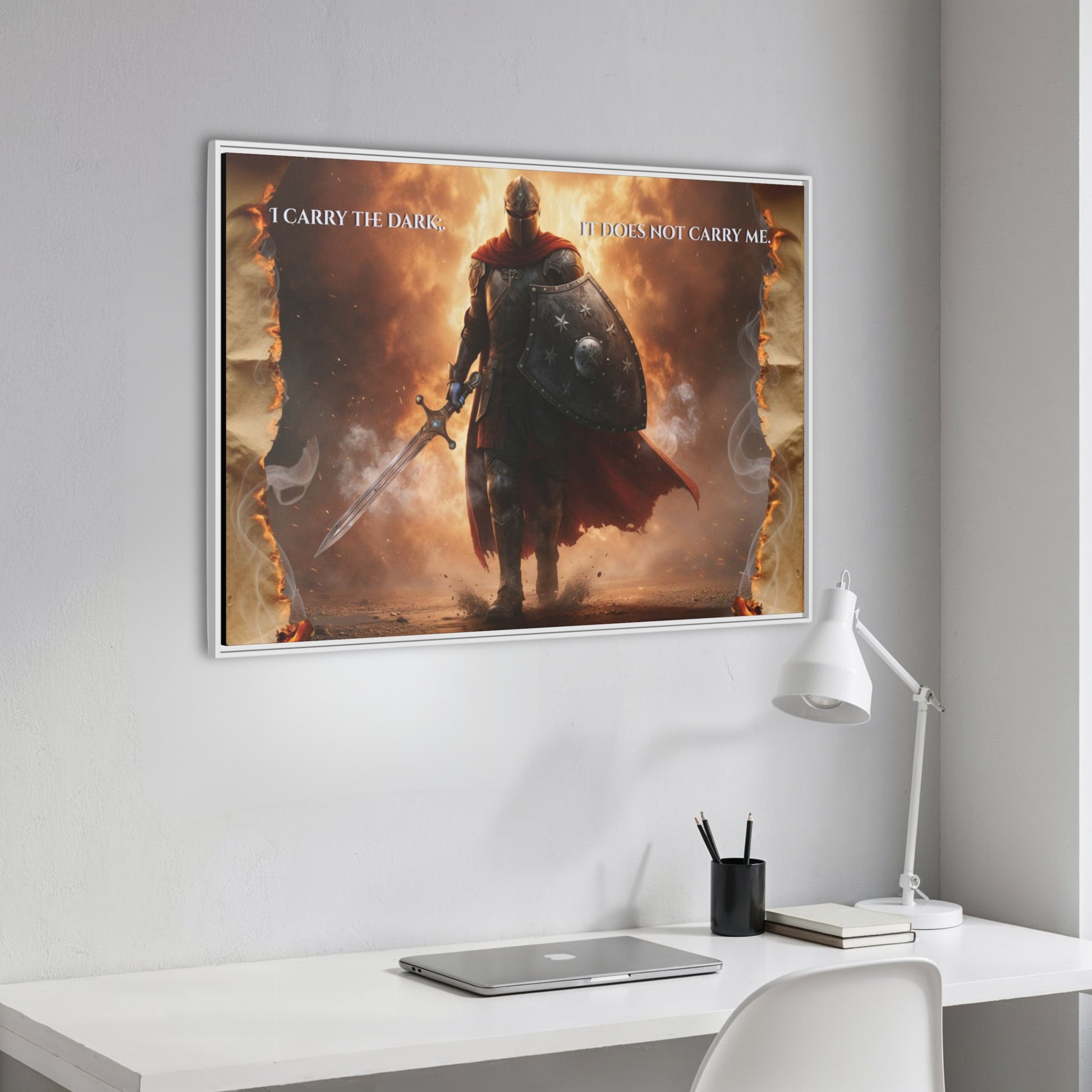 Angled close-up of the knight-in-fire framed canvas with the quote ‘I carry the dark; it does not carry me’ hanging above a minimalist white desk.