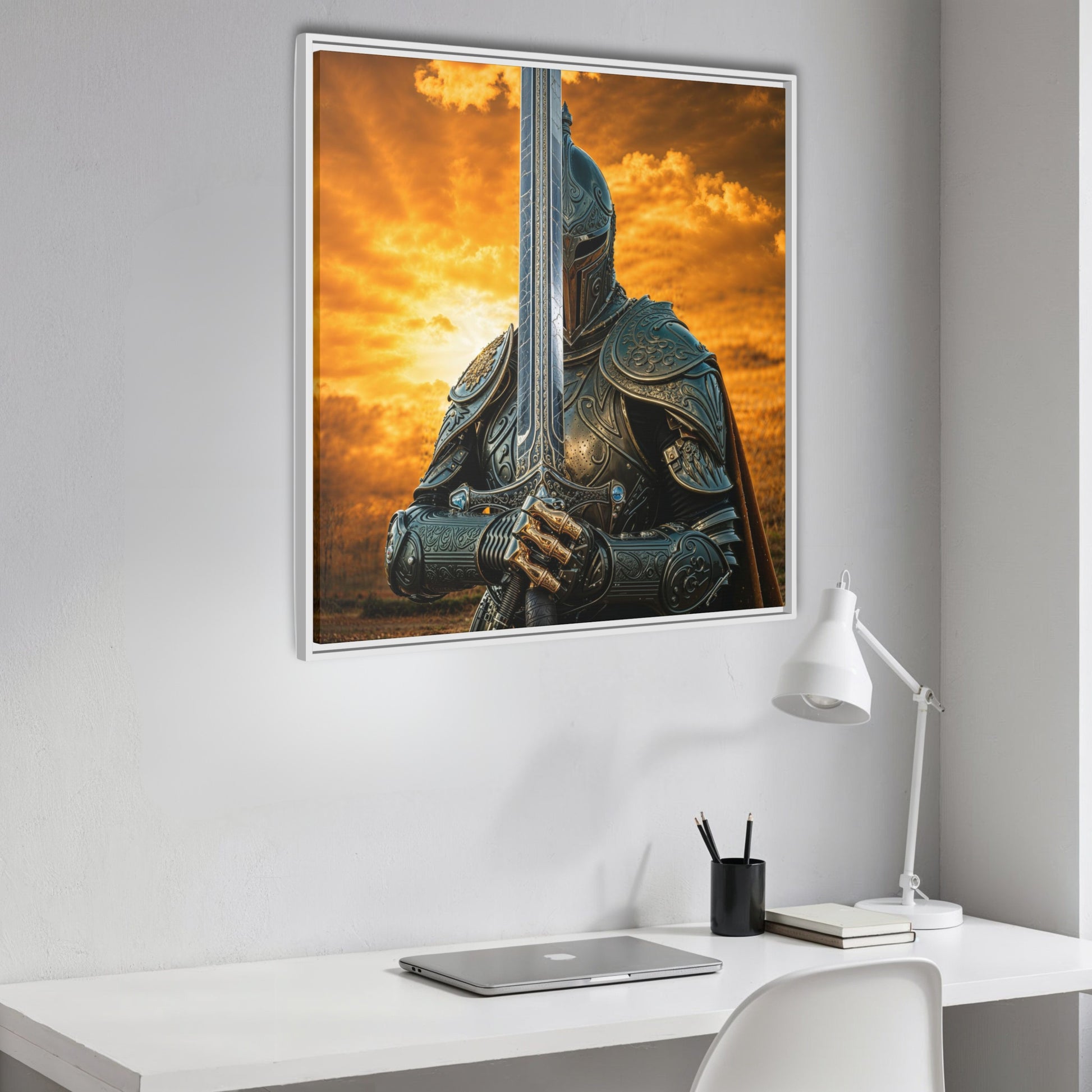 Side angle of white framed knight and sword canvas from Chapter 1 hanging above a white desk with laptop and lamp.