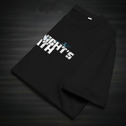 Folded black “The Knight’s Path” organic t-shirt laid on a dark surface, showing the cracked white logo and a blue arrow across the chest.