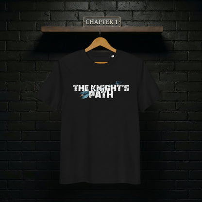 Black “The Knight’s Path” organic tee on a wooden hanger against a black brick wall with a Chapter 1 shelf sign above.