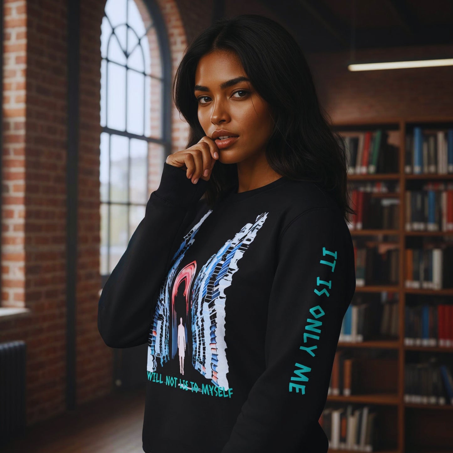 Amara in a brick-walled library wearing the Chapter 1 black sweatshirt, front artwork of book stacks and red arch with the vow “I WILL NOT LIE TO MYSELF”.