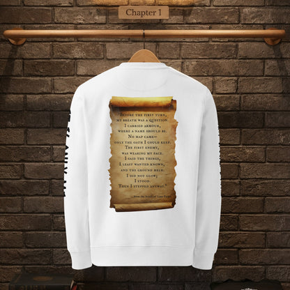 Back view of white sweatshirt on hanger against brick wall, featuring large parchment scroll quote from The Knight’s Path.