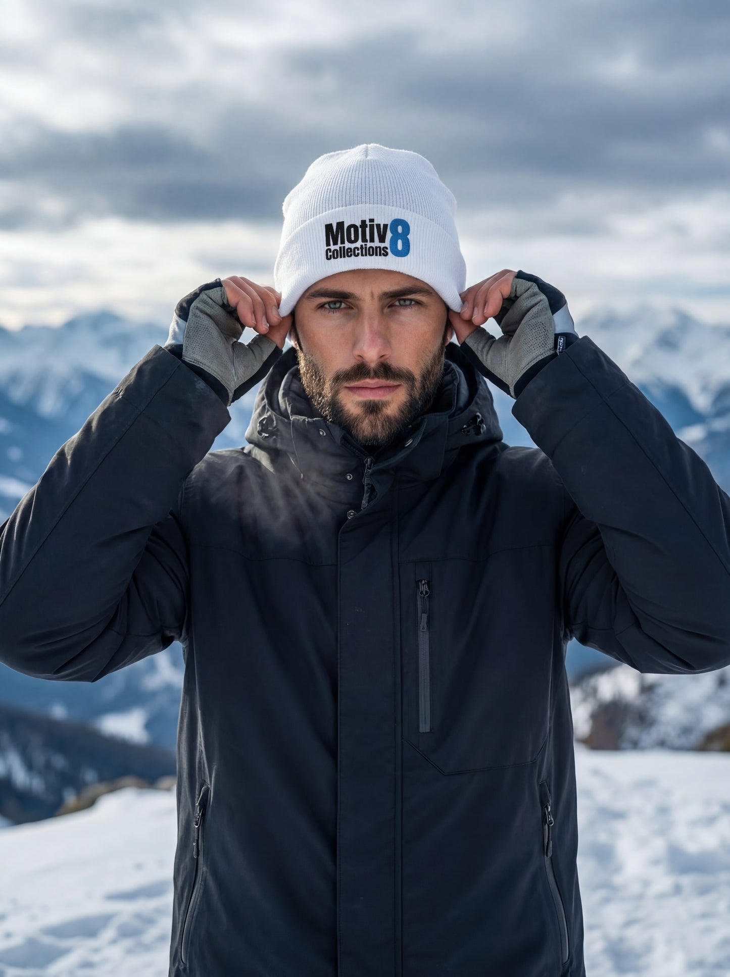 Adrian Holt tightening white Motiv8 Collections beanie on icy mountain summit, focused expression in cold alpine air.