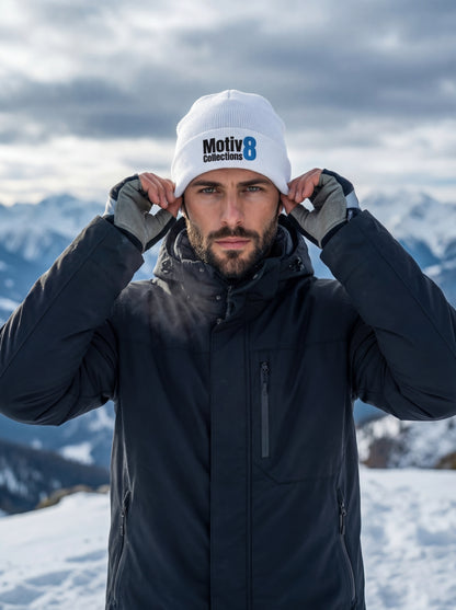 Adrian Holt tightening white Motiv8 Collections beanie on icy mountain summit, focused expression in cold alpine air.