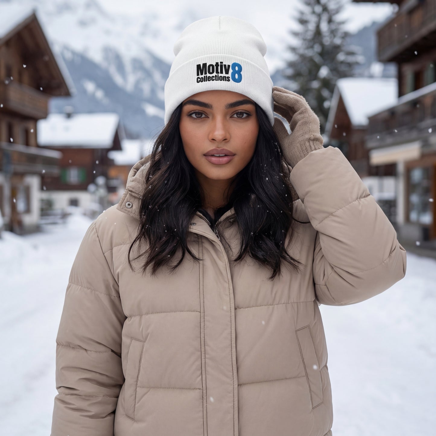 Amara Solis wearing white Motiv8 Collections beanie and puffer jacket in snowy alpine village, motivational cold-weather look