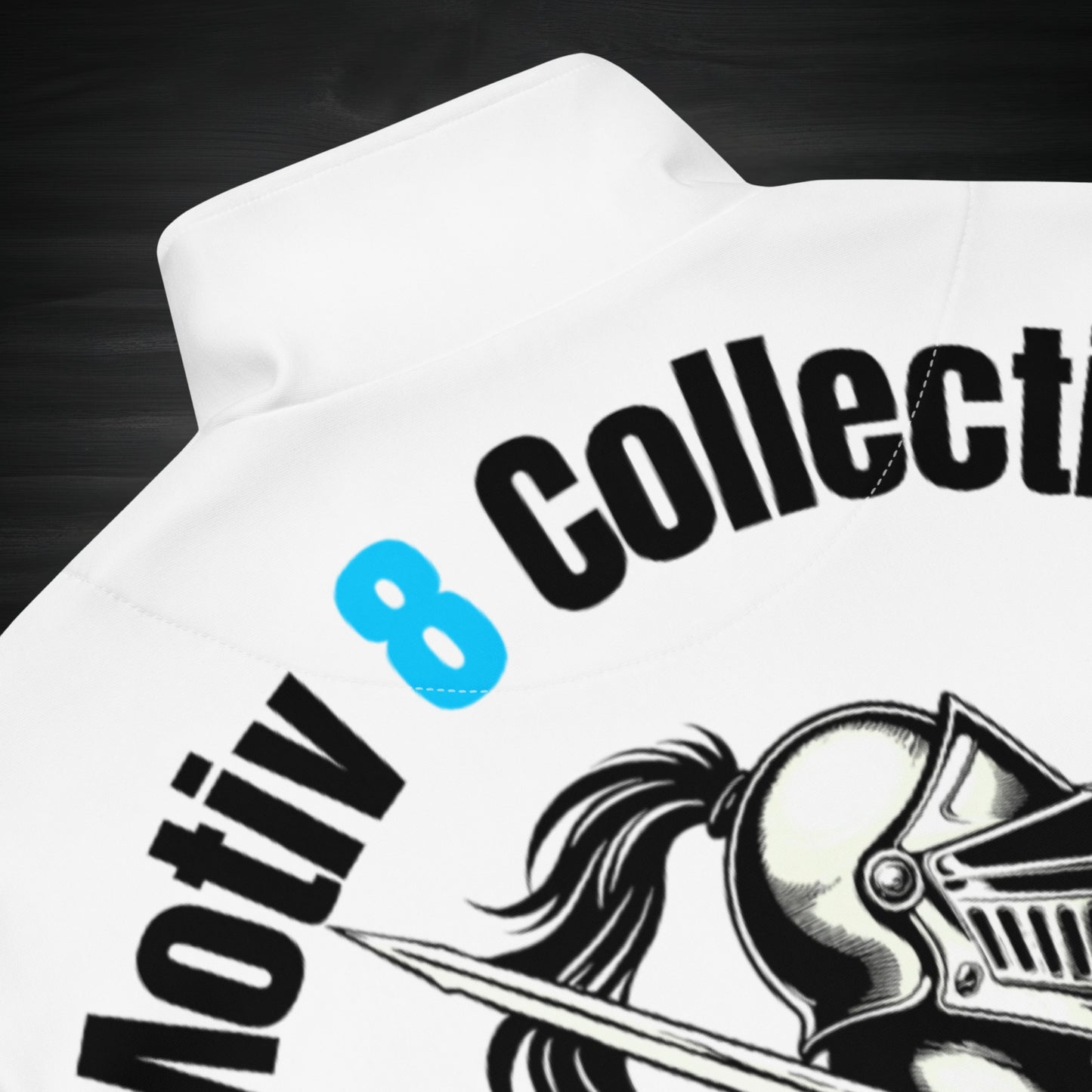 Close-up of the back neck of the white Motiv8 Collections track jacket, showing the crisp “Motiv 8 Collections” lettering and fine line knight artwork printed on smooth recycled fabric for a quality detail shot.