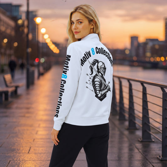 Back view of Elena in the white Motiv8 Collections track jacket on the riverside path at dusk, highlighting the armoured knight with arrows and curved “Motiv 8 Collections” print across the shoulders and sleeves.