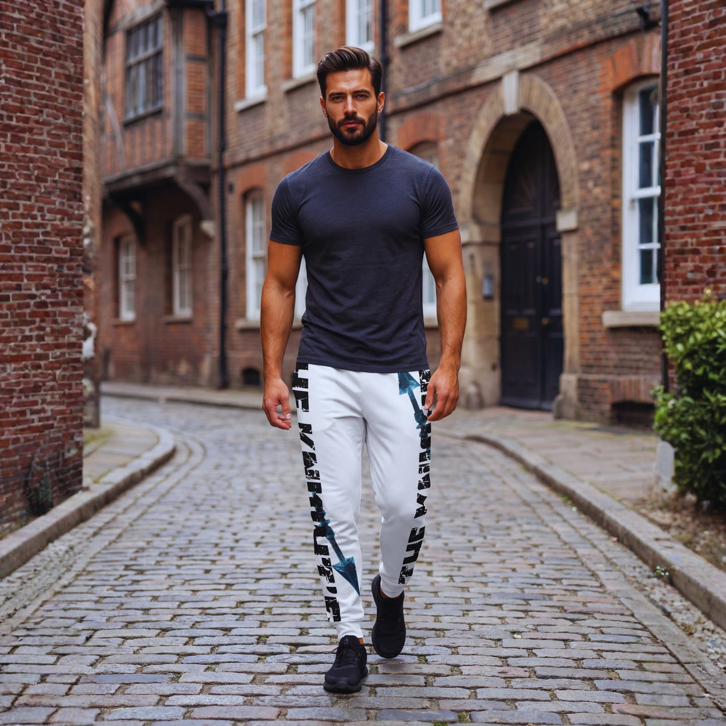 Adrian wearing Motiv8 Collections The Knight’s Path “Arrow One” white joggers, walking down a cobblestone street with bold side text and blue arrow graphic.
