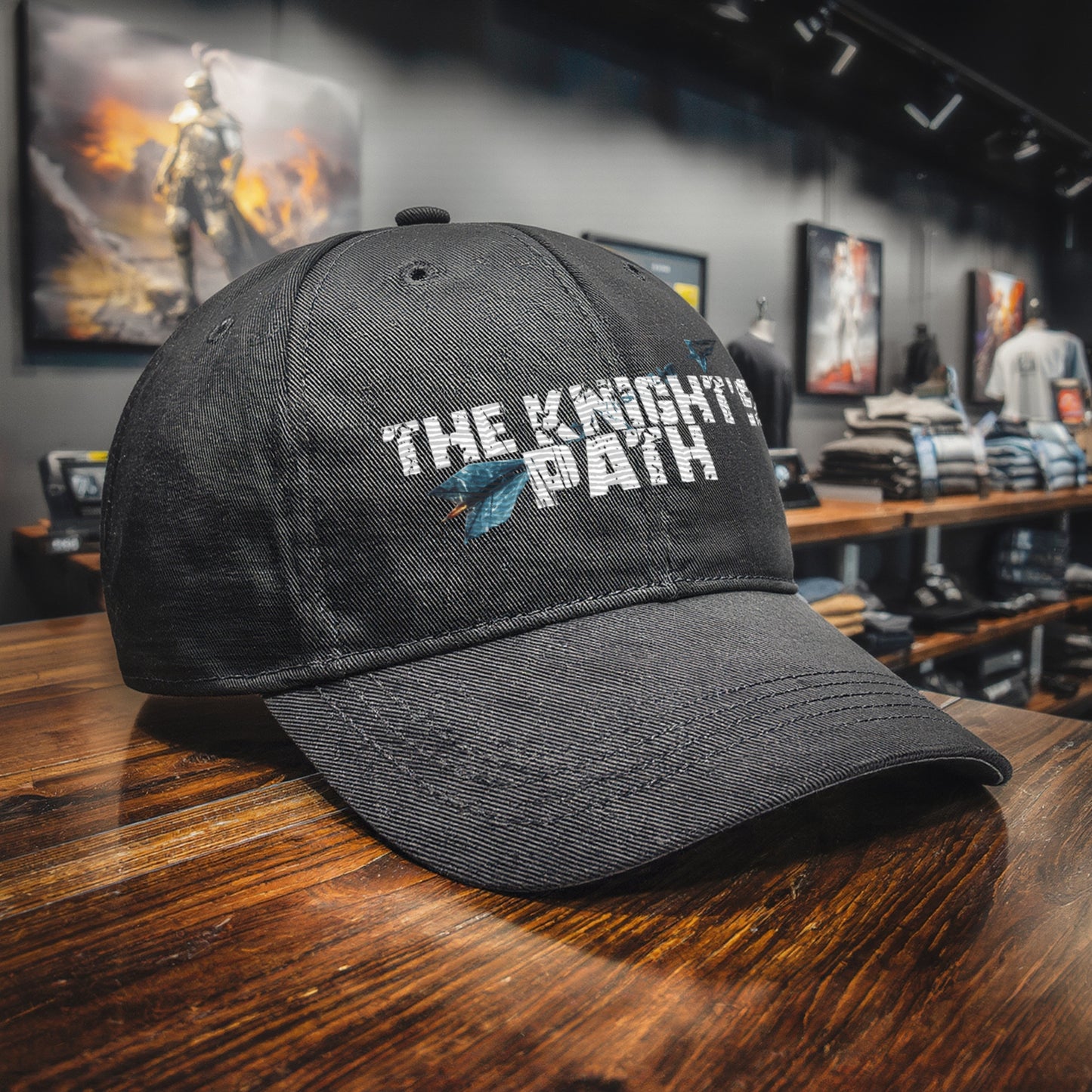 Black “The Knight’s Path” Chapter 1 cap resting on a wooden counter in a fantasy-style Motiv8 Collections shop, embroidered logo with crystal arrow clearly visible in the foreground.