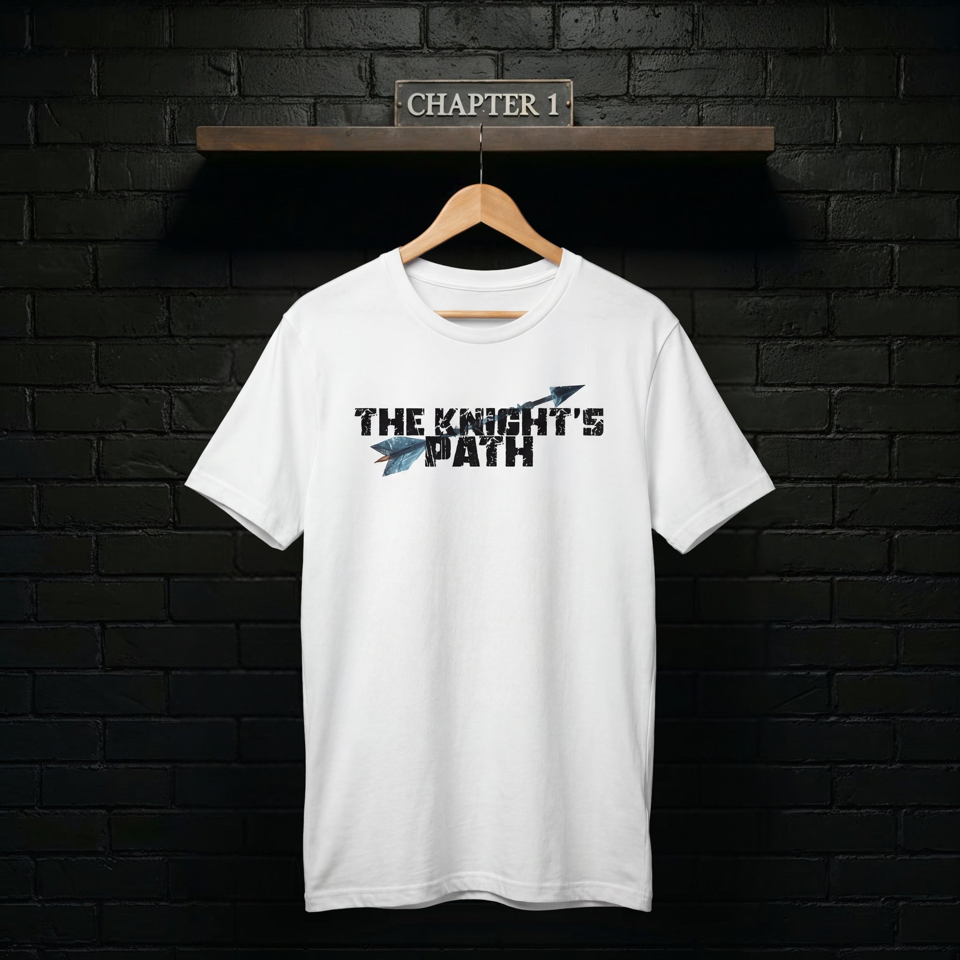 The Knight’s Path Chapter 1 white t-shirt on a wooden hanger against a black brick wall with “Chapter 1” sign, clean product mockup highlighting the arrow logo.